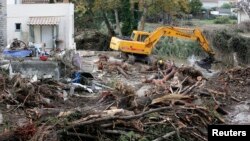 A mechanical digger clears away debris from trees in a stream near a house the day after torrential rains caused flooding in Biot, France, Oct. 5, 2015. 