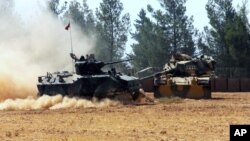A Turkish army tank and an armored vehicle are stationed near the border with Syria, in Karkamis, Turkey, Aug. 23, 2016. Turkish media reports say Turkish artillery on Tuesday launched new strikes at Islamic State targets across the border in Syria.