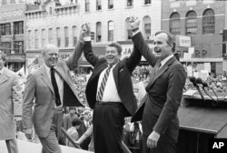 FILE - Former president Gerald Ford, left, lends his support to fellow Republican and presidential candidate Ronald Reagan and running mate George Bush, seen here on the final day of campaigning in Peoria, Ill., Nov. 3, 1980.