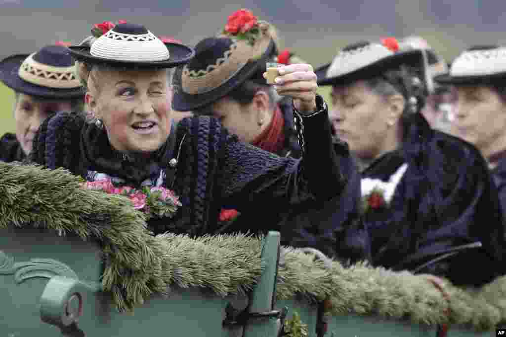 A woman salutes with liqueur as she sits in a horse-drawn carriage during the traditional Leonhardi pilgrimage in Warngau, Germany.