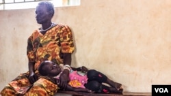 After crossing Nimule border, a woman and her child wait for a medical check up at Elegu reception center. (N. Jidovanu/VOA)