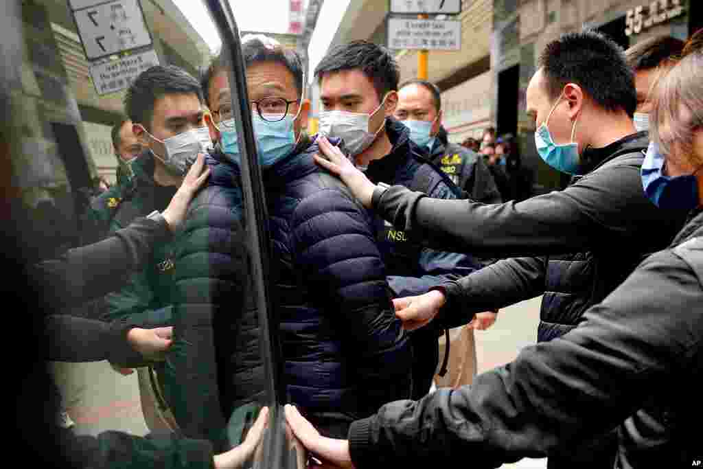 Patrick Lam, center, the editor of Stand News, is escorted by police officers into a van after they searched evidence at his office in Hong Kong.