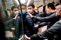 FILE - Patrick Lam, center, the editor of Stand News, is escorted by police officers into a van after they searched evidence at his office in Hong Kong.