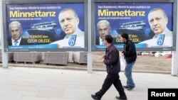 Dua orang pejalan kaki mengamati papan bergambar PM Turki Tayyip Erdogan (kanan) dan PM Israel Benyamin Netanyahu (kiri), di Ankara, 25 Maret 2013 (Foto: dok).