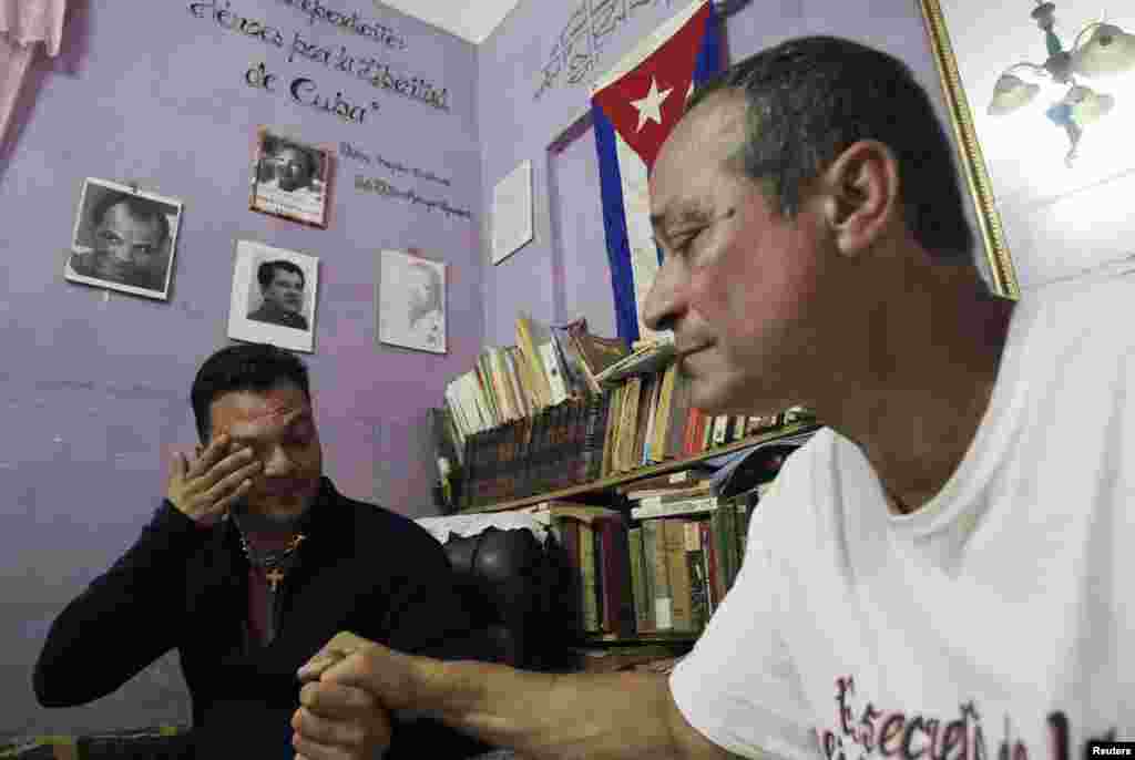 Reinier Figueredo (left) reacts while holding his father Angel&#39;s hand at their home. Angel Figueredo and his wife Haydee Gallardo (not pictured), members of the &quot;Ladies in White&quot; dissident group, were detained last year after shouting anti-government slogans at a rally, in Havana, Cuba, Jan. 8, 2015.