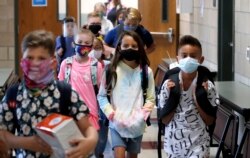 FILE - Wearing masks to prevent the spread of COVID19, elementary school students walk to classes to begin their school day in Godley, Texas, Wednesday, Aug. 5, 2020. (AP Photo/LM Otero)