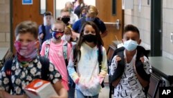 Wearing masks to prevent the spread of COVID19, elementary school students walk to classes to begin their school day in Godley, Texas, Wednesday, Aug. 5, 2020. (AP Photo/LM Otero)