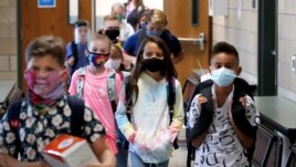 FILE - Wearing masks to prevent the spread of COVID19, elementary school students walk to classes to begin their school day in Godley, Texas, Wednesday, Aug. 5, 2020. (AP Photo/LM Otero)