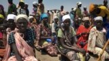 Sejumlah perempuan duduk di tanah, sedang mengantre untuk menerima makanan yang didistribusikan oleh Program Pangan Dunia (WFP) di Padeah, Sudan Selatan. (Foto: AP)