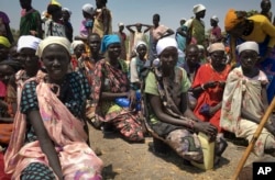 FILE - Women sit in line on the ground waiting to receive food distributed by the World Food Program (WFP) in Padeah, South Sudan, March 1, 2017.