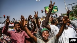 Sudanese protesters chant slogans and flash victory signs as they continue to demonstrate outside the army complex in Khartoum, April 17, 2019. They hardened their demand that the military men in power quickly step down.