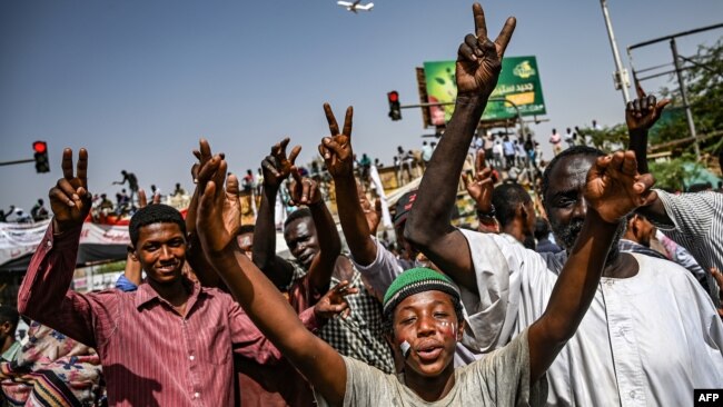 Sudanese protesters chant slogans and flash victory signs as they continue to demonstrate outside the army complex in Khartoum, April 17, 2019. They hardened their demand that the military men in power quickly step down.