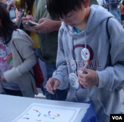 Brian Manivong membuat lukisan dengan belatung di gerai Maggot Monet di pameran sains dan teknik nasional Washington DC