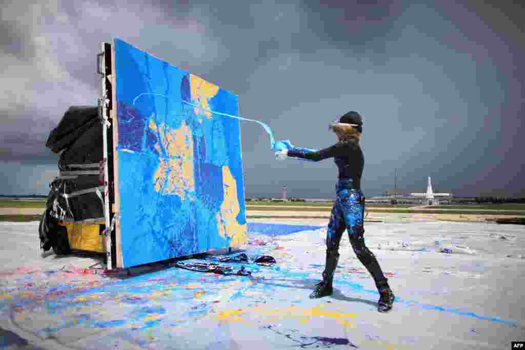 Artist Princess Tarinan von Anhalt throws paint into the flow of air coming from the engine of Flexjet’s Learjet 40 XR engine to create a painting on a canvas at Signature Flight Support in West Palm Beach, Florida, USA, Apr. 30, 2013.