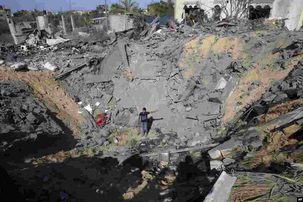 A Palestinian youth stands in the hole of a destroyed house following overnight Israeli missile strikes, in Al-Qarara, east of Khan Younis, southern Gaza Strip.