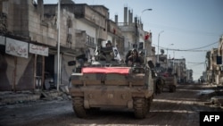 Turkish army vehicles drive on a street in Kobani, Syria, during an operation to relieve the garrison guarding the Suleyman Shah mausoleum in northern Syria, Feb, 22, 2015, 