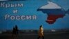 People walk past a mural showing a map of Crimea in the Russian national colors on a street in Moscow, Russia, March 25, 2014.