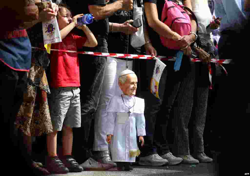 A man holds a puppet of the Pope Francis as they wait for his arrival for a meeting with patients of the Cottolengo hospital in Turin, Italy.