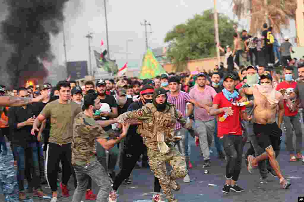 Anti-government protesters help a soldier from the Federal Police Rapid Response Forces to get out of the protest site area after other protesters beat him, in Baghdad, Iraq.
