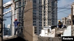 FILE - Workers rest as they demolish an old residential site in the center of Shanghai, September 15, 2013. 