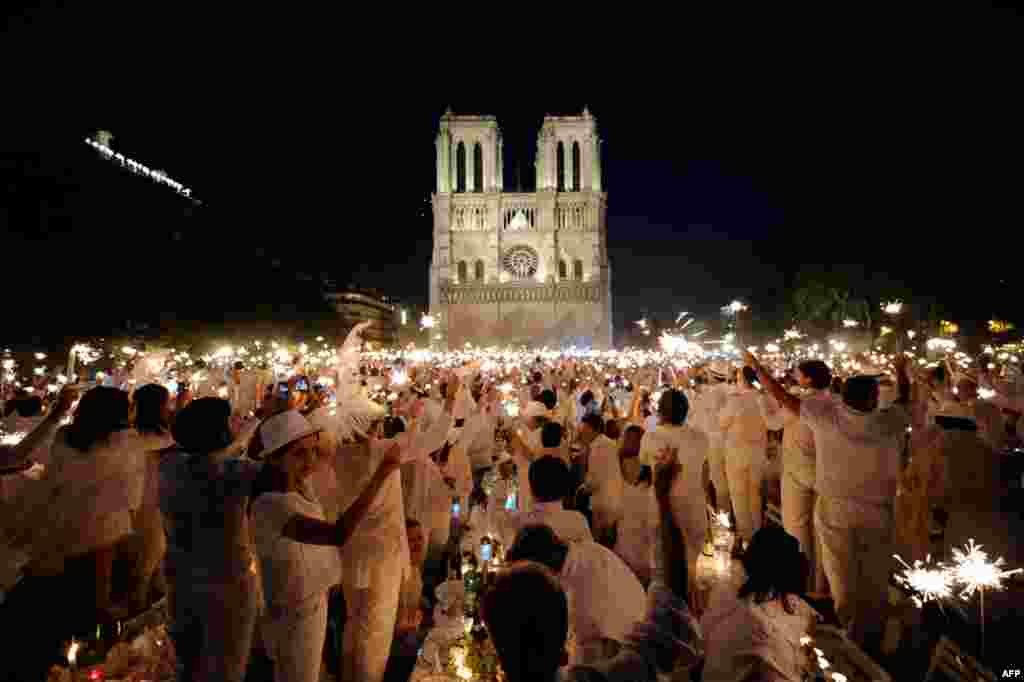 June 16: People celebrate with sparklers as they attend the White Dinner event in front of the Notre Dame Cathedral in Paris. Participants attend the dinner, which takes place at a different place in Paris every year, are required to be dressed in white,