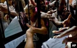 Santeria followers reach out for copies of the annual Letter of the Year, written by Afro-Cuban Santeria priests outlining predictions for the new year in Havana, Cuba, Jan. 3, 2017.