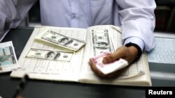 A man counts US dollars and Burma kyats at a money changer in Rangoon, March 21, 2012. 