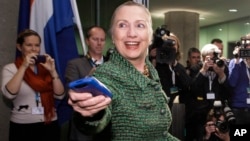 ລັດຖະມົນຕີການຕ່າງປະເທດ Hillary Clinton ມອບໂທລະສັບມືຖືຂອງທ່ານນາງ ຕອນທີ່ພົບປະກັບ ທ່ານ Uri Rosenthal ລັດຖະມົນຕີການຕ່າງປະເທດ Netherlands ໃນນະຄອນ Hague, Netherlands, 8 ທັນວາ, 2011.