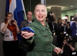 FILE - Then-U.S. Secretary of State Hillary Clinton hands off her mobile phone after arriving to meet with Dutch Foreign Minister Uri Rosenthal at the Ministry of Foreign Affairs in The Hague, Netherlands, Dec. 8, 2011.