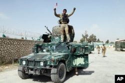 FILE - In this Oct. 2, 2015, file photo, an Afghan soldier raises his hands as a victory sign, in Kunduz city, north of Kabul, Oct. 2, 2015 after retaking the city.