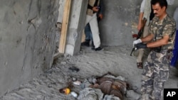 An Afghan security officer stands near the body of an insurgent killed in a battle near Kabul airport, Afghanistan, June, 10, 2013. 