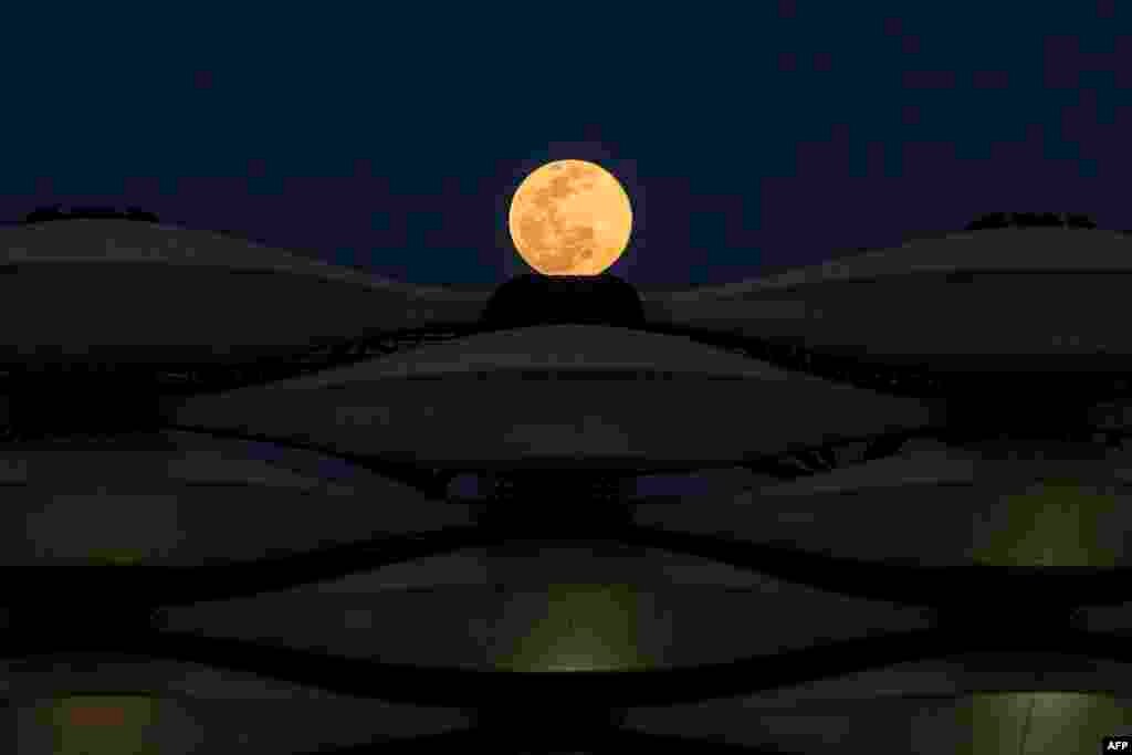 A view of the rising full &quot;Worm Moon&quot; above Basra International Stadium in the southern Iraqi city, March 28, 2021.