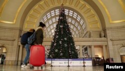 Para calon penumpang kereta melintas di depan pohon Natal di stasiun kereta Union Station di tengah pandemi virus corona, di Washington, Rabu, 23 Desember 2020. (Foto: Reuters)