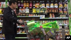 A man pushes a shopping cart past a display of nuts imported from the United States and other countries at a supermarket in Beijing, April 2, 2018. 