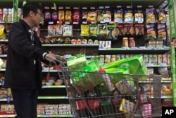 A man pushes a shopping cart past a display of nuts imported from the United States and other countries at a supermarket in Beijing, April 2, 2018.