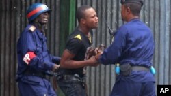 An anti government protestor, center, is arrested by FILE - Congo riot troops, during a protest against a new law that could delay elections to be held in 2016, in the city of Kinshasa, Democratic Republic of Congo, Jan. 19, 2015.