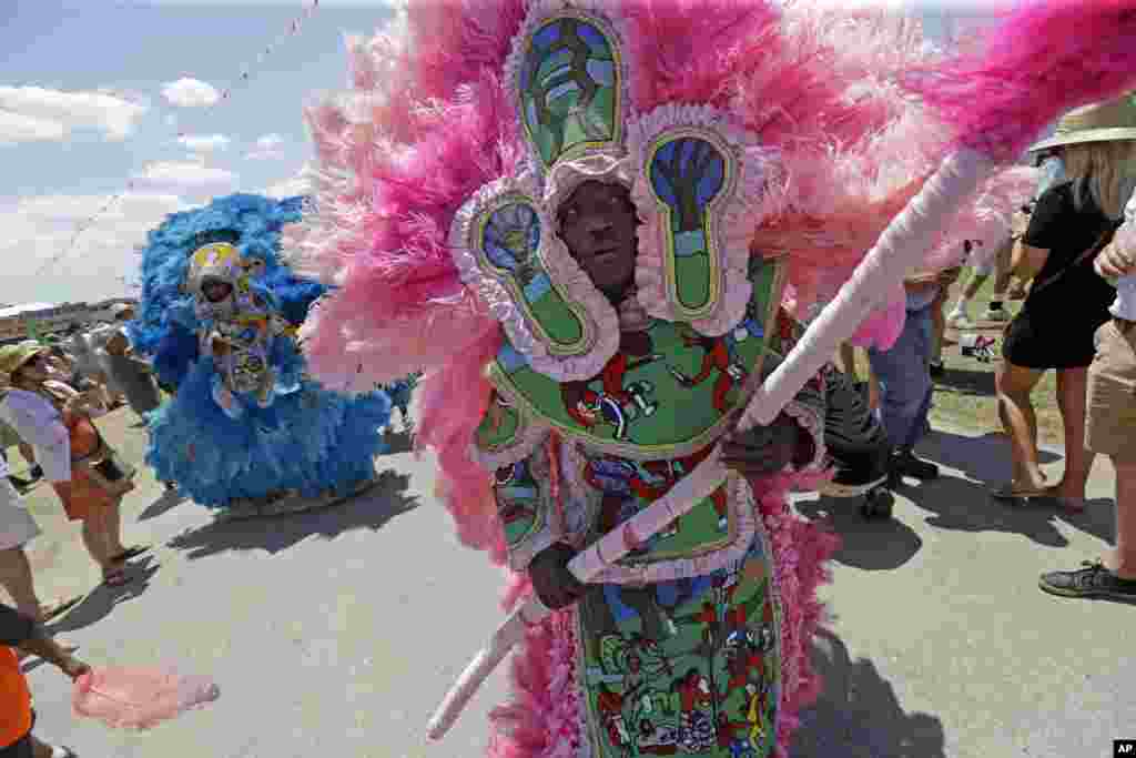 Members of the New Orleans Mardi Gras Indian Rhythm Section, with the Algiers Warriors and Golden Comanche Mardi Gras Indians, march in a second line parade at the New Orleans Jazz and Heritage Festival in New Orleans, Louisiana.