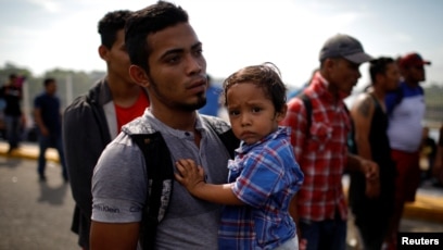 Un migrante salvadoreño que viaja a los Estados Unidos lleva a su hijo en la frontera entre Guatemala y México, en Tecun Uman, Guatemala, el 18 de enero de 2020.