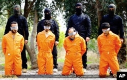 This undated image released by a militant website, which has been verified and is consistent with other AP reporting, shows members of the Islamic State group as they prepare to kill men who were allegedly spying for the U.S.-led coalition.