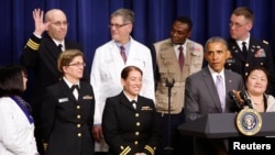 A member of the U.S. military Ebola response team raises his hand in recognition as U.S. President Barack Obama (2nd R) mentions him in his remarks about the progress made in the response to the Ebola outbreak in West Africa, the White House, Washington, Feb. 11, 2015.