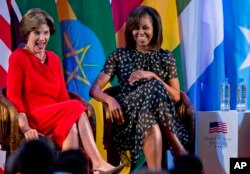 FILE - U.S. first lady Michelle Obama, right, and former U.S. first lady Laura Bush laugh as they participate in an African First Ladies Summit in Dar es Salaam, Tanzania, July 2, 2013.