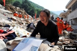 A woman cries over an album on the debris of her house at the earthquake zone of Longtoushan town, Ludian county, Zhaotong, Yunan province, China, Aug. 6, 2014.