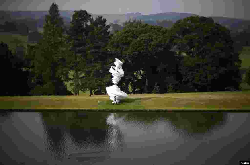 A woman walks past a sculpture by Alice Aycock entitled &quot;Cyclone Twist&quot; during the Beyond Limits selling exhibition at Chatsworth House in central England. 