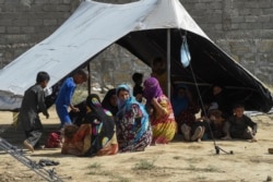 FILE - Afghan refugees sit around a makeshift tent shelter on the outskirts of Quetta, Pakistan, Sept. 6, 2021.