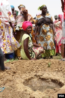 Women in Senegal's Woudourou village watch as workers from the Hadii Yahde project teach them to plant guava trees, May 17, 2017. (S. Christensen/VOA)
