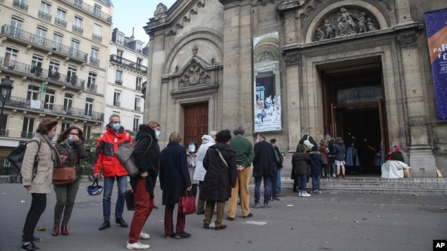 Church-goers wearing face masks as a precaution against the coronavirus lineup outside the Notre-Dame-des-Champs church in Paris, Sunday, Nov. 29, 2020. 