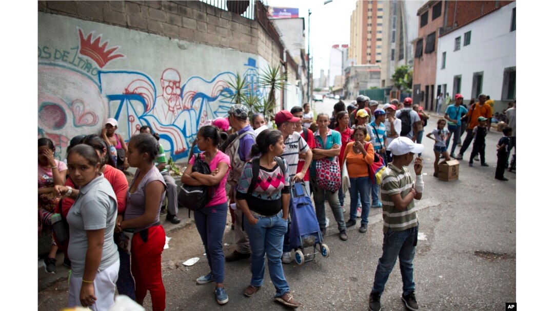 FILE - People wait in line for subsidized food staples, such as beans, rice, tuna and powdered milk, provided by the government program CLAP, which stands for Local Committees of Supply and Production, in Caracas, Venezuela, May 16, 2018.