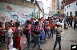 FILE - People wait in line for subsidized food staples, such as beans, rice, tuna and powdered milk, provided by the government program CLAP, which stands for Local Committees of Supply and Production, in Caracas, Venezuela, May 16, 2018.