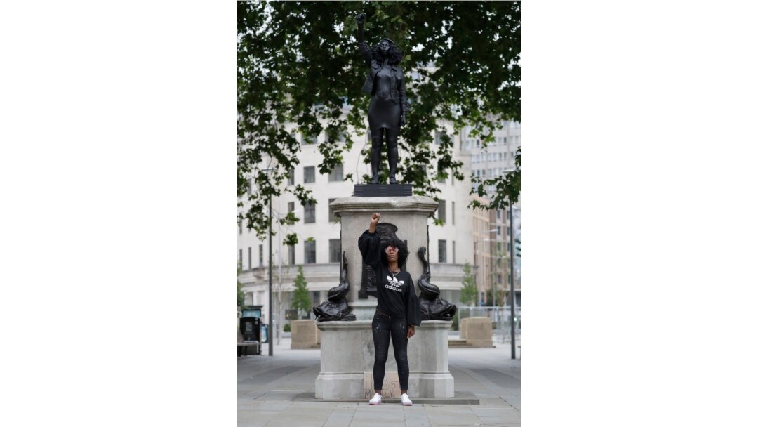 Jen Reid berpose di depan resin hitam dan patung baja baru yang menggambarkan dirinya, yang diberi judul "A Surge of Power (Jen Reid) 2020" karya seniman Marc Quinn, di Bristol, Inggris, 15 Juli 2020.