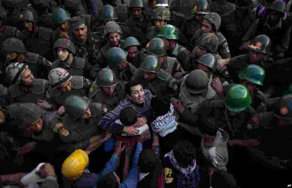 Protesters push army soldiers standing guard in front of the presidential palace in Cairo, Egypt, December 9, 2012. 